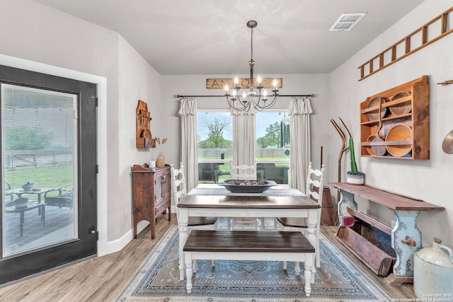 dining area with visible vents, baseboards, an inviting chandelier, and wood finished floors