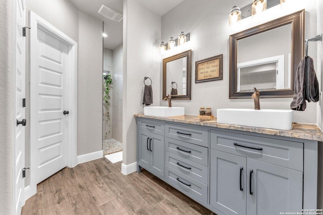 full bathroom with a walk in shower, visible vents, a sink, and wood finished floors