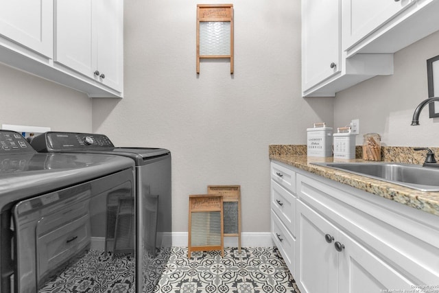 laundry area with a sink, baseboards, cabinet space, and washing machine and dryer