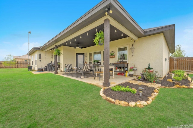 back of property featuring a yard, fence, and stucco siding