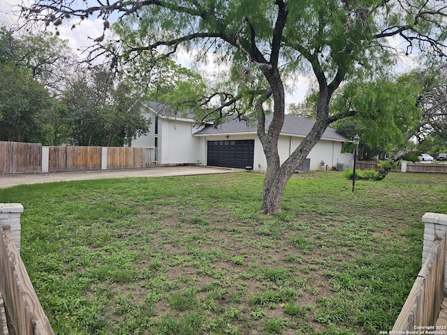 view of yard featuring driveway, a garage, and fence
