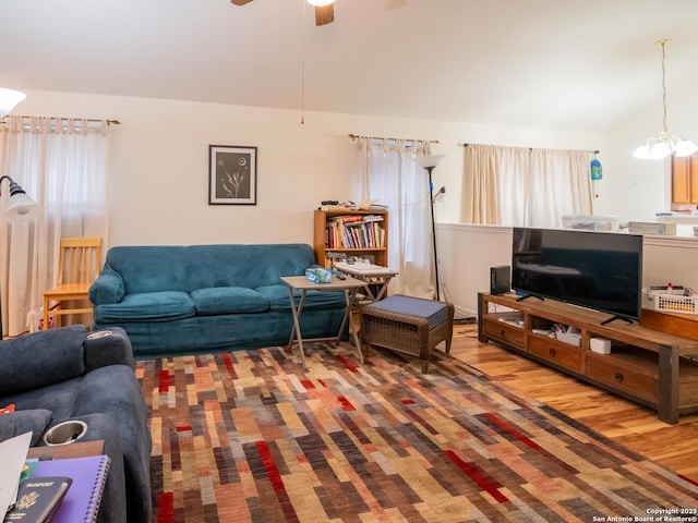 living room featuring ceiling fan with notable chandelier, vaulted ceiling, and wood finished floors