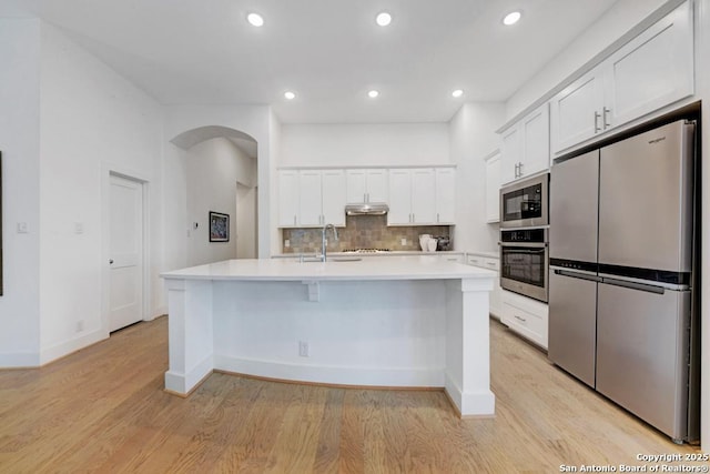 kitchen featuring under cabinet range hood, white cabinets, stainless steel appliances, and light countertops