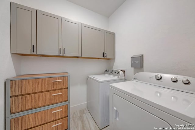 laundry room featuring light wood finished floors, separate washer and dryer, and cabinet space