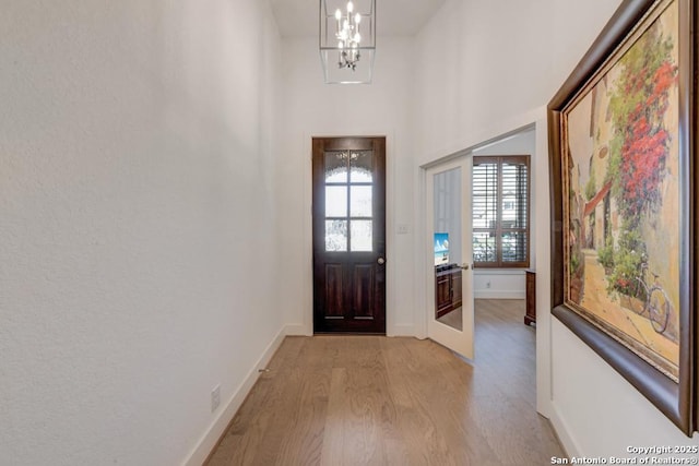 entrance foyer featuring a chandelier, baseboards, and light wood finished floors