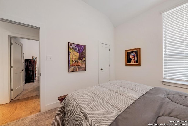 bedroom with baseboards, lofted ceiling, and light colored carpet