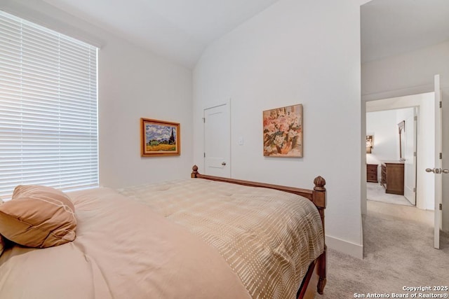 bedroom with lofted ceiling and light colored carpet