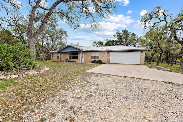 2501 Fischer Store, Wimberley, TX 78676 - view of front of home with concrete driveway, a chimney, brick siding, a garage, and metal roof