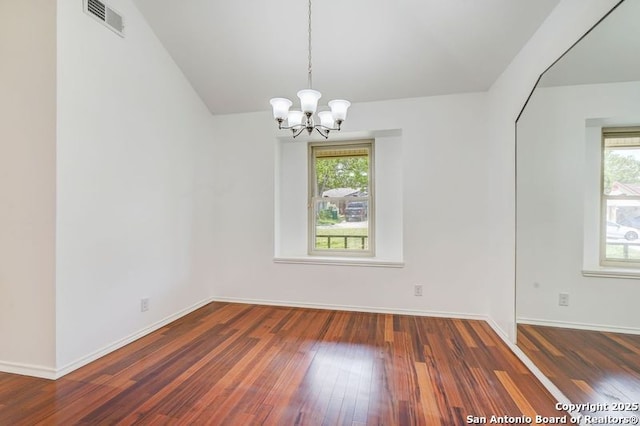 unfurnished room with baseboards, visible vents, an inviting chandelier, and hardwood / wood-style flooring