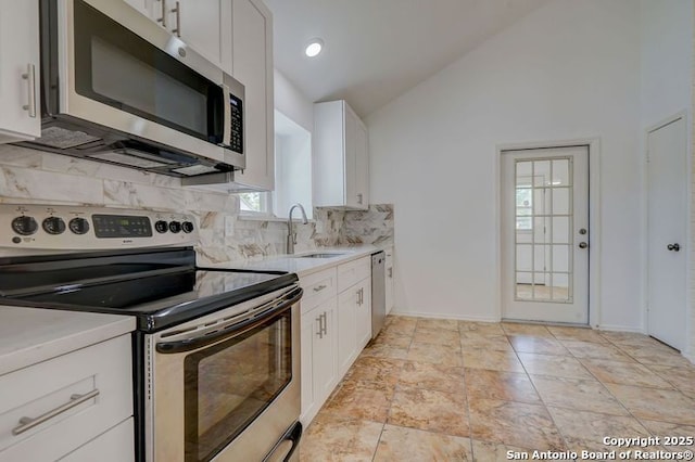 kitchen with light countertops, a sink, appliances with stainless steel finishes, and lofted ceiling