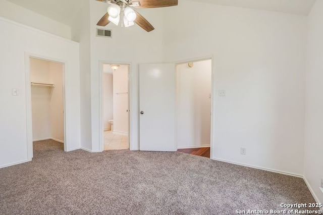 unfurnished bedroom featuring a spacious closet, high vaulted ceiling, carpet floors, connected bathroom, and visible vents