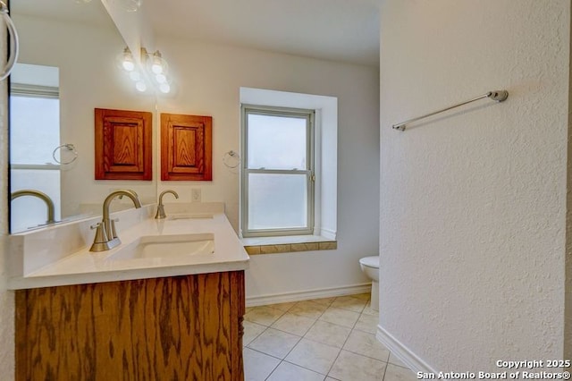 bathroom with baseboards, a sink, toilet, and tile patterned flooring