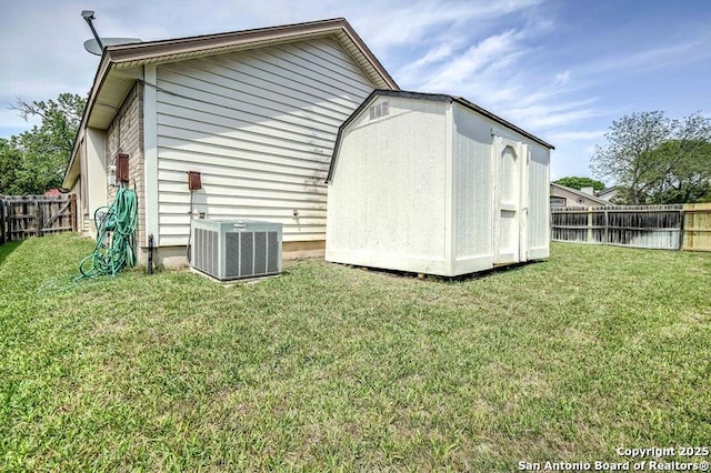 exterior space featuring an outdoor structure, a fenced backyard, a storage unit, central AC, and a yard