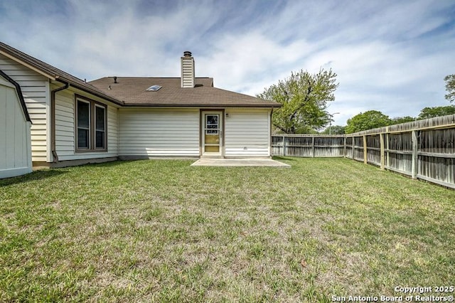 rear view of house with a chimney, fence, a yard, and a patio area