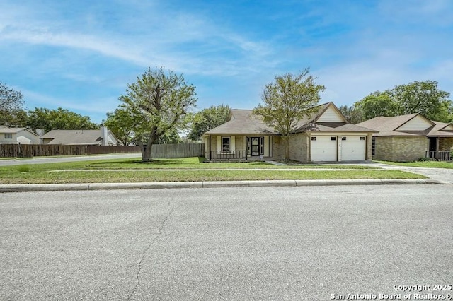 ranch-style home with driveway, an attached garage, fence, and a front yard