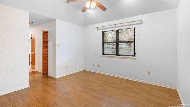 spare room with baseboards, wallpapered walls, a ceiling fan, and wood finished floors