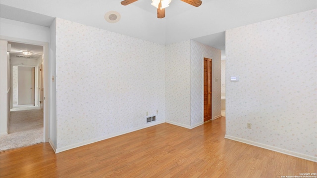 spare room featuring wallpapered walls, light wood-style flooring, and visible vents