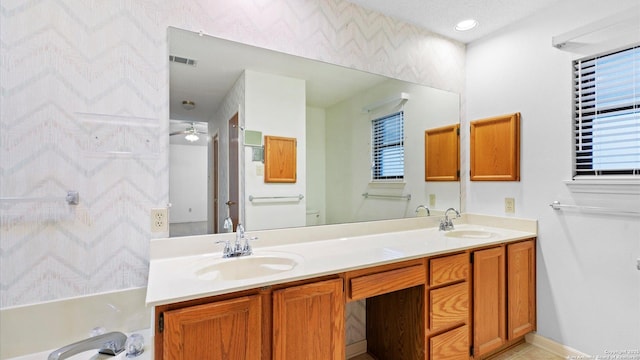 bathroom with double vanity, a sink, a bathtub, and visible vents