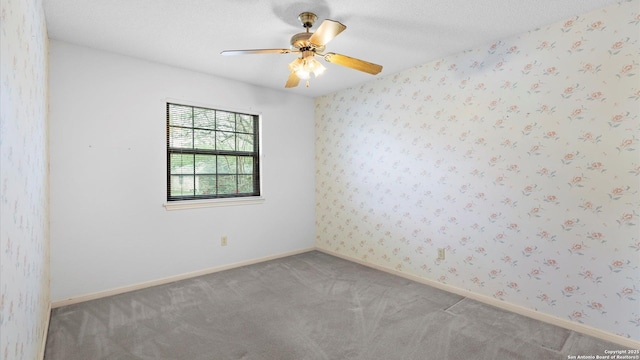 unfurnished room with carpet, baseboards, a textured ceiling, wallpapered walls, and a ceiling fan