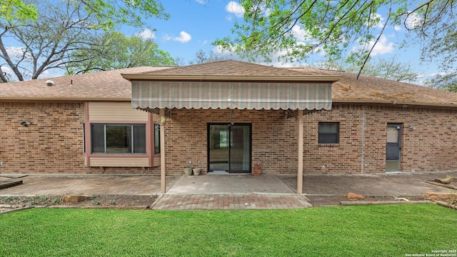 rear view of house featuring brick siding, a lawn, and a patio