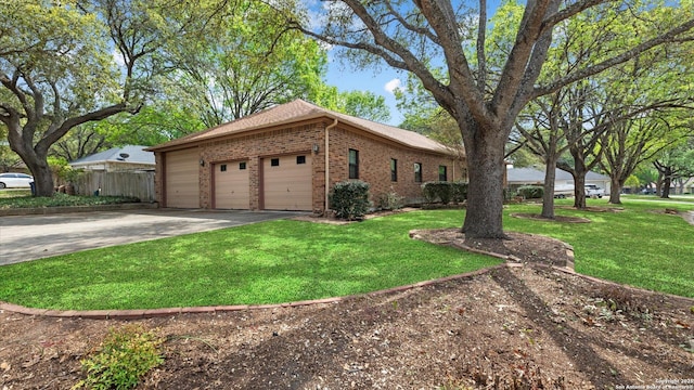 view of side of property with a yard, an attached garage, brick siding, and concrete driveway