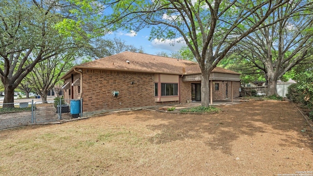 rear view of property with a gate, a patio area, fence, brick siding, and a yard
