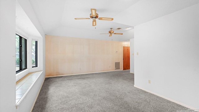 carpeted spare room with lofted ceiling, baseboards, ceiling fan, and visible vents
