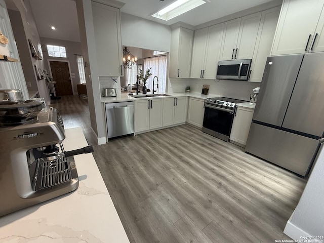 5038 Fawn Lake Dr, San Antonio, TX 78244 - kitchen with decorative backsplash, a chandelier, light wood finished floors, appliances with stainless steel finishes, and a sink