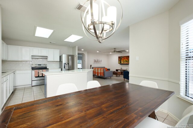 7102 Valley Trl, San Antonio, TX 78250 - dining space with light tile patterned floors, a skylight, and ceiling fan with notable chandelier