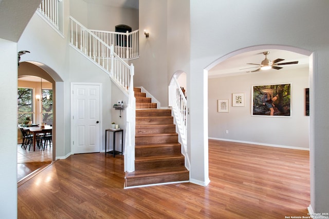 19423 Camino Rdg, San Antonio, TX 78258 - stairway with arched walkways, wood finished floors, a ceiling fan, a towering ceiling, and baseboards