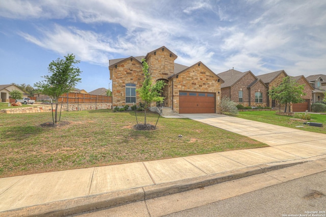 view of front of house featuring driveway, stone siding, fence, an attached garage, and a front lawn
