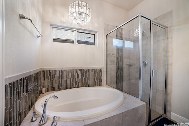 bathroom with a shower stall, a chandelier, and a garden tub
