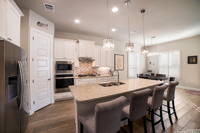 kitchen with visible vents, stainless steel appliances, under cabinet range hood, a sink, and backsplash