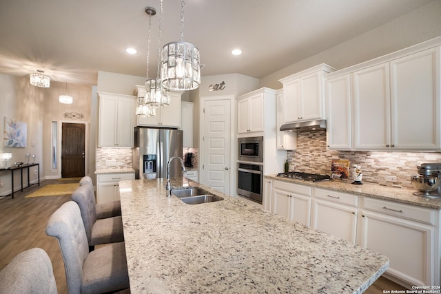 kitchen featuring a sink, white cabinetry, appliances with stainless steel finishes, under cabinet range hood, and a kitchen island with sink