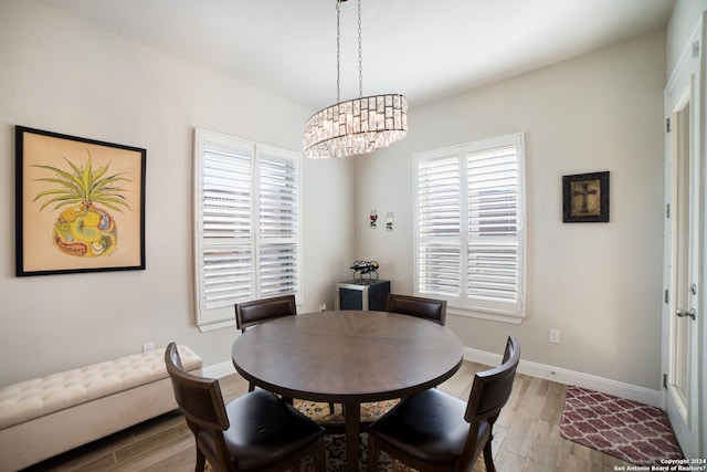 dining room featuring baseboards, wood finished floors, and an inviting chandelier