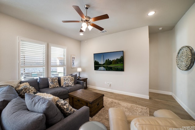 living room featuring baseboards, visible vents, a ceiling fan, and wood finished floors