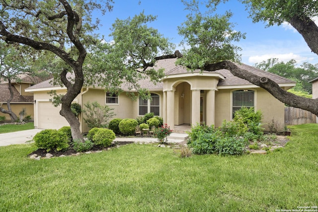 mediterranean / spanish home with a front lawn, stucco siding, a shingled roof, an attached garage, and driveway