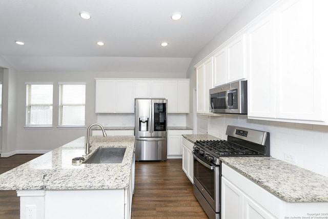 kitchen with dark wood-style flooring, a kitchen island with sink, a sink, and appliances with stainless steel finishes