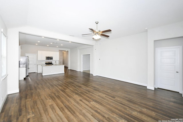 unfurnished living room with baseboards, dark wood-style flooring, a sink, and a ceiling fan