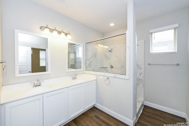 bathroom with a marble finish shower, baseboards, a sink, and wood finished floors