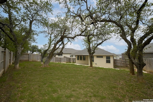 back of house with a fenced backyard and a yard