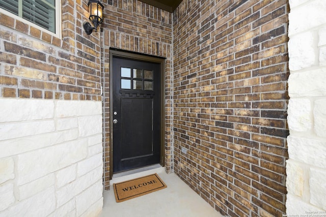 view of exterior entry featuring brick siding