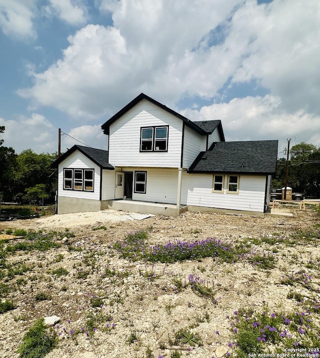 back of house featuring a patio and roof with shingles