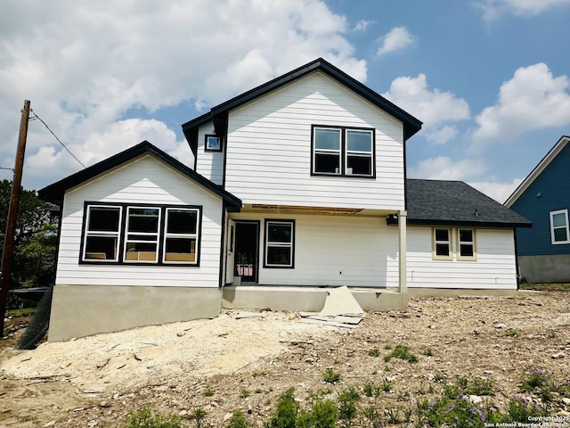 back of property with a shingled roof and a patio