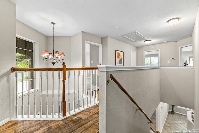 13911 Laurelbrook, San Antonio, TX 78249 - hallway featuring a notable chandelier, an upstairs landing, attic access, wood finished floors, and baseboards
