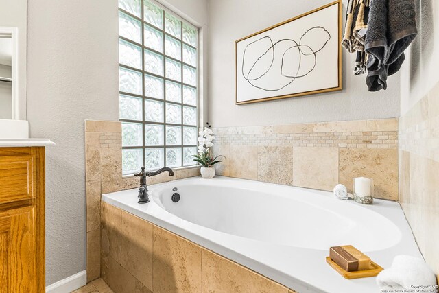 13911 Laurelbrook, San Antonio, TX 78249 - bathroom featuring a textured wall, a garden tub, vanity, and plenty of natural light