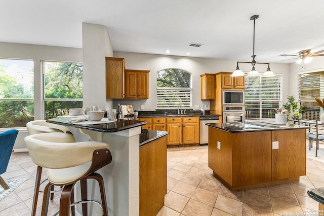 13911 Laurelbrook, San Antonio, TX 78249 - kitchen featuring stainless steel appliances, hanging light fixtures, a sink, dark countertops, and brown cabinets
