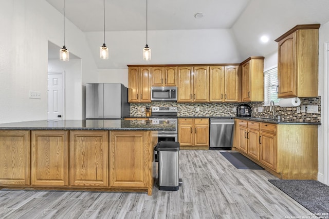 24704 Killarney St, Hempstead, TX 77445 - kitchen with stainless steel appliances, dark stone countertops, a sink, light wood-style floors, and brown cabinetry