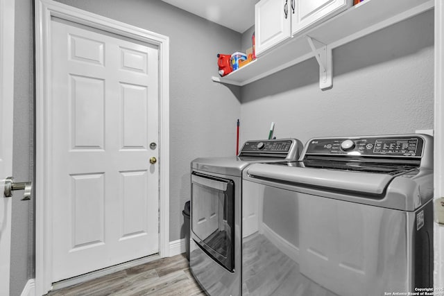 24704 Killarney St, Hempstead, TX 77445 - washroom with washing machine and dryer, light wood-type flooring, and cabinet space