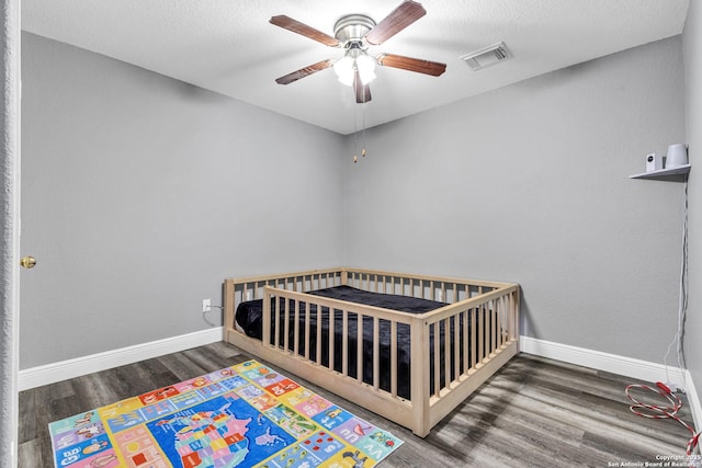 24704 Killarney St, Hempstead, TX 77445 - bedroom featuring baseboards, visible vents, wood finished floors, ceiling fan, and a nursery area